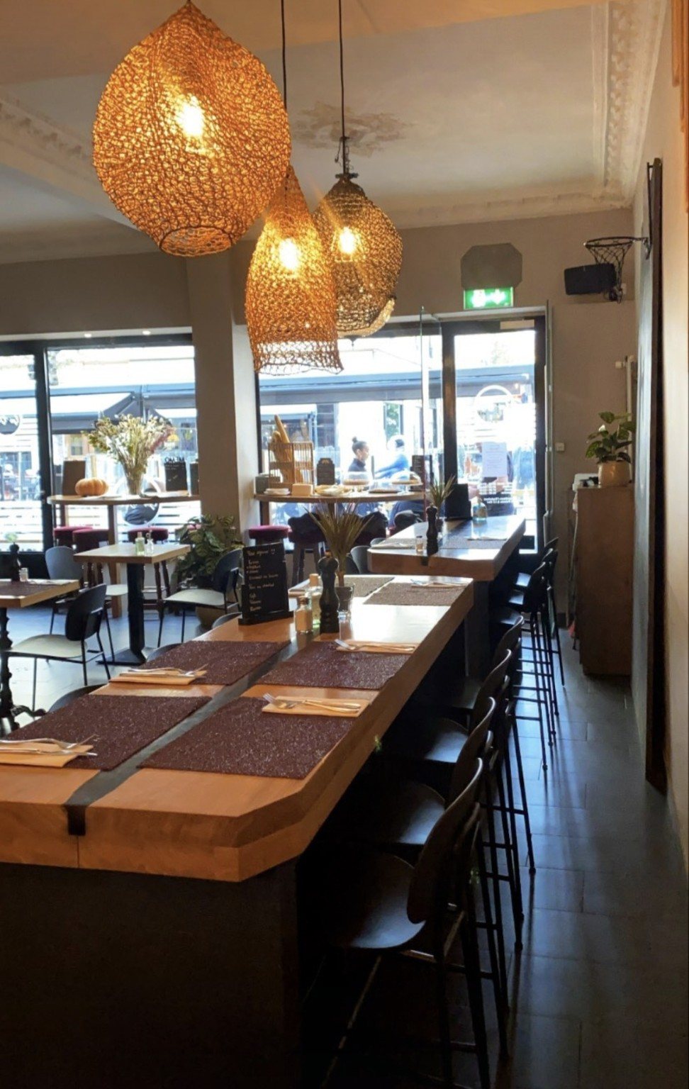 Grande table en bois sous des luminaires tressés.